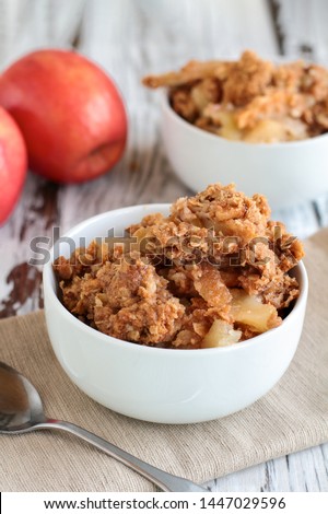 Fresh hot homemade apple crisp or crumble with crunchy streusel topping topped in a bowl with fresh apples in background. Selective focus with blurred background. 