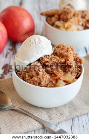 Fresh hot homemade apple crisp or crumble with crunchy streusel topping topped with vanilla bean ice cream. Selective focus with blurred background. 