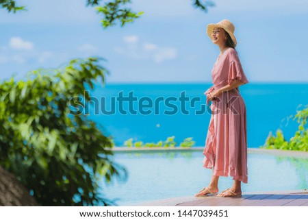 Portrait young asian woman relax smile happy around outdoor swimming pool in hotel resort with sea ocean view in holiday vacation concept