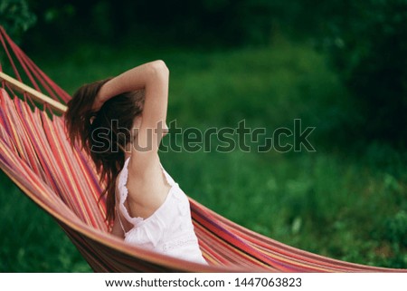 A woman in bright clothes is lying in a hammock on the back side of nature