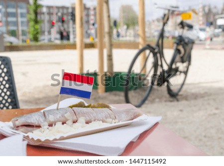 Slised herring with flag of Netherlands. Onion and cucumber. Bicycle on the background.