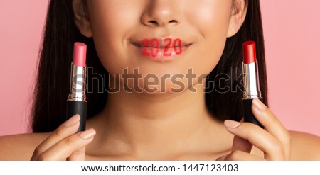 2020 trends concept. Asian woman choosing lipstick with lettering 2020 on lips, close up, panorama