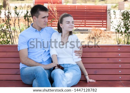 beautiful young couple sitting on a bench in the park. Portrait