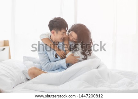Asian couple sitting on bed together, they hug each other with love, concept for spending time with lover. Royalty-Free Stock Photo #1447200812