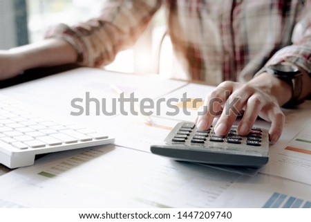 Close up Business woman using calculator and laptop for do math finance on wooden desk in office and business working background, tax, accounting, statistics and analytic research concept
