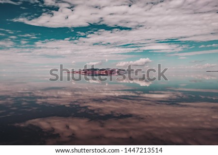 Dreamy water reflections of clouds and tall peaks on Great Salt Lake at Antelope Island State Park, Utah, USA.  Royalty-Free Stock Photo #1447213514