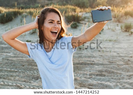 Beautiful young woman having a good time at the beach on a lovely day, taking a selfie