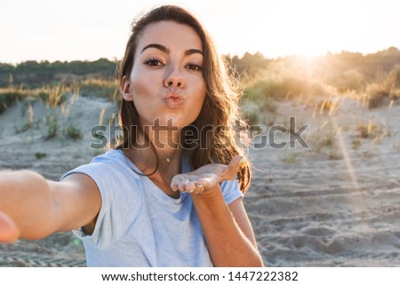 Beautiful young woman having a good time at the beach on a lovely day, taking a selfie, sending kiss
