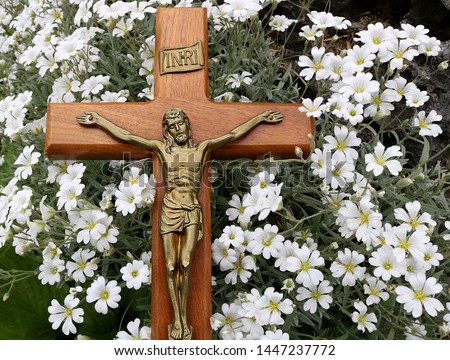 Crucifix laying in patch of small white Snow in Summer flowers. Concept that though our sins are as scarlet Jesus will make them white as snow