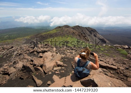 woman mountain climber resting and taking pictures on the crater rim of vulcano mount Etna