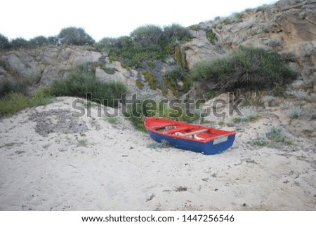 Blue-red wooden boat on the sandy beach in Sarti on Sithonia (also known as Longos) peninsula of Chalkidiki. Nature background. Touristic place.