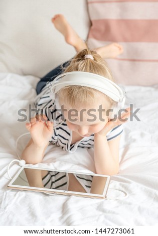Caucasian Little Girl in Headphone Watching Tablet in Bed, Home Interior, Modern Device Technologies Scandinavian Style