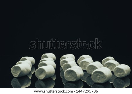 White marshmallow on a black glass table background.