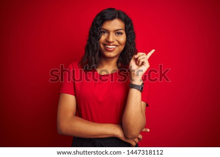 Beautiful transsexual transgender woman wearing t-shirt over isolated red background with a big smile on face, pointing with hand and finger to the side looking at the camera.