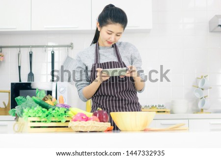 Asian young woman is preparing healthy food on light kitchen ,she use mobile phones to take pictures of food,Healthy food concept.