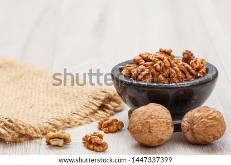 Walnuts in stone bowl with sackcloth on a wooden background. Useful nutritious protein product. Shallow depth of field.