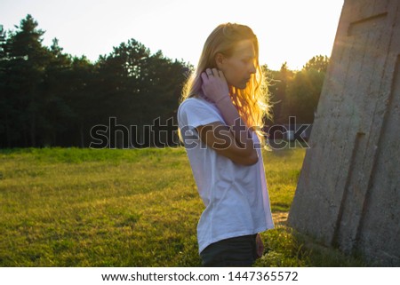 Blonde woman in white t shirt and sunset behind. Summer photo of blonde woman