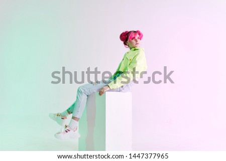 woman with pink hair sits on a fashion cube