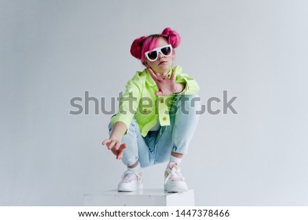 stylish woman with hairstyle in glasses sits on a cube