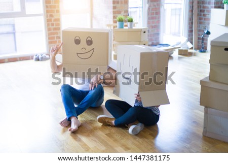 Couple wearing funny cardboard boxes with happy faces, moving to