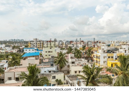 A scenic aerial view of a town with beautiful dark cloud formation and covered with coconut trees in between, as photographed from building terrace and real estate development