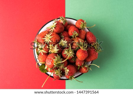 Flat lay Red ripe juicy strawberry in a plate, over red and green background.