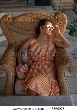 Young woman wearing striped dress is relaxing in chair enjoying sunset