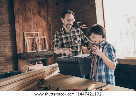 Portrait of two nice person cheerful cheery glad successful woodworkers master handyman dad giving new toolkit to son production industry at modern loft industrial brick interior