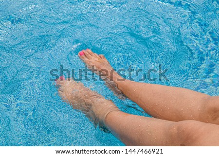 Female legs in the pool. Summer holiday concept.