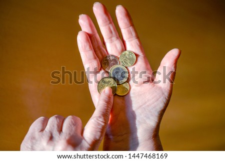 Poor elderly woman is counting some Euro and Cents coins in her hand - selective focus with little depth of field, isolated