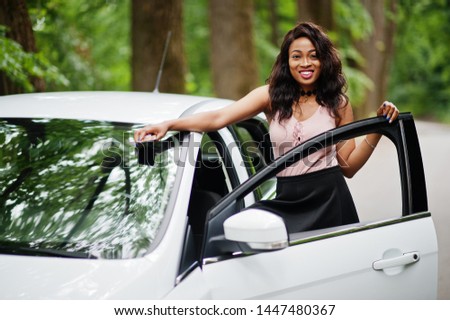 African american woman posed against white car in forest road.