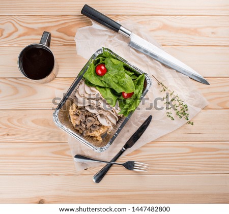 Turkey fillet with couscous, mushrooms and spinach leaves on light wooden background. Take-away. Dietary and healthy food.