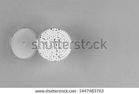 open plastic box with cotton swabs on grey background top view, black and white photo