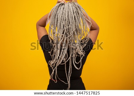 Beautiful young african american woman on her back showing her hair with dread on yellow background