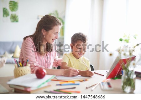 mother helps son to do lessons. home schooling, home lessons. the tutor is engaged with the child, teaches to write and count. out-of-school lessons with a teacher. happy baby in bright room with mom Royalty-Free Stock Photo #1447548686