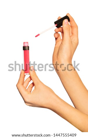 Female hands holding lip gloss tube and applicator Royalty-Free Stock Photo #1447555409