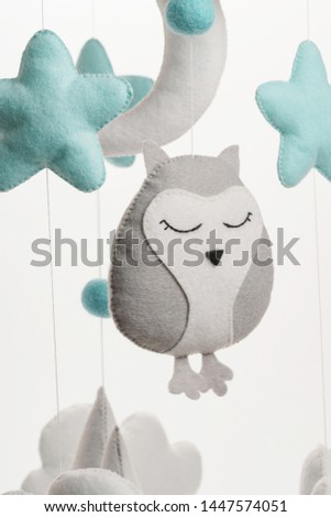 A felt toy in the form of a lowely owl, part of a children's mobile. On a white background. Colorful and eco-friendly children's mobile from felt for children.