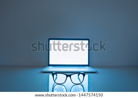 Computer eyeglasses in front of a laptop, low-key image. Blue light blockers and laptop in dark background, eye fatique problem concept