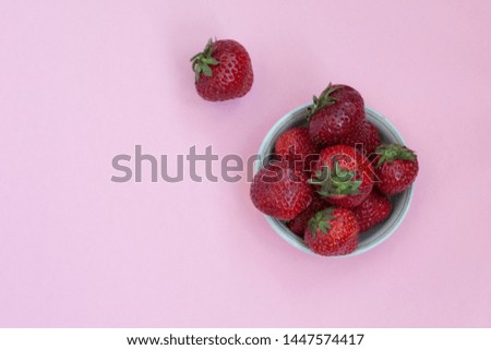 Ripe red strawberries in a plate. Pink background. Foods with vitamins. Vegetarian food.