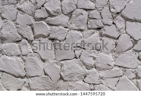Fragment of wall of natural stones covered with white plaster. Texture. Background
