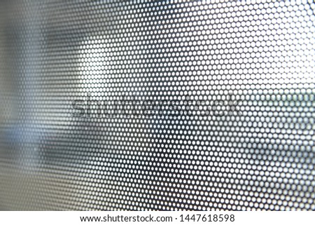 Black toning mesh on glass with small holes in the airport. Selective focus.  Closeup abstract dot glass with raster gradient halftone. Psychedelic effect. Blurred object outlines.
