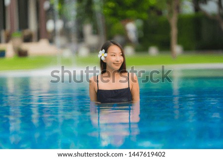 Portrait young asian woman relax smile happy around outdoor swimming pool in hotel resort with sea ocean view in holiday vacation concept