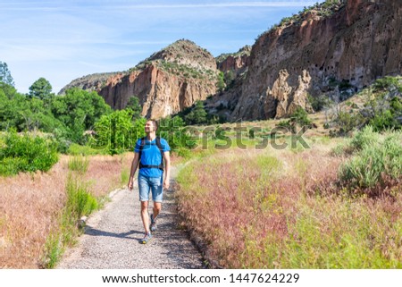 Main Loop path trail with man walking in Bandelier National Monument in New Mexico in Los Alamos with canyon cliffs Royalty-Free Stock Photo #1447624229