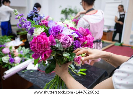 Female florist create a bouquet at workplace. Floristics workshop. Making beautiful flower bouquets and floral decorations.
