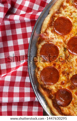 Fresh Homemade Pizza on Red and white checkered table cloth on a wood table with copy space, vertical format.