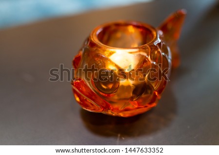 Closeup of glass object with illuminated lit tea candle lamp on table traditional Japanese goldfish decoration