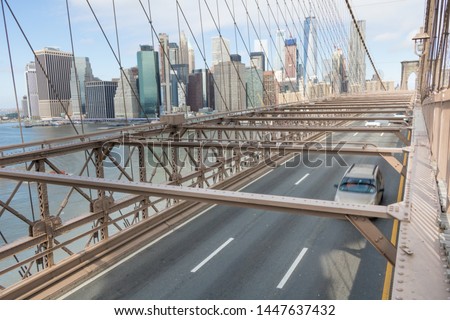 Cars traveling over the Brooklyn Bridge. City of Manhattan in the background. New York, USA.
