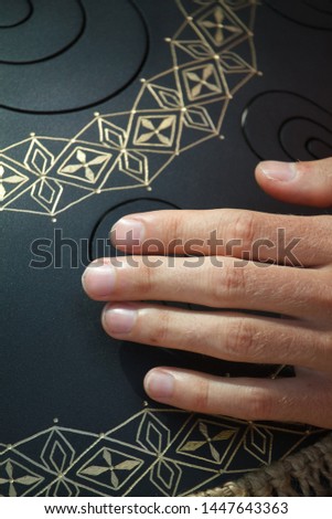 Closeup of a mans hand playing on modern musical instrument Hand pan or Vadjraghanta or metal tongue drumon, selective focus
