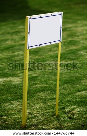 An empty white billboard on a green grass background