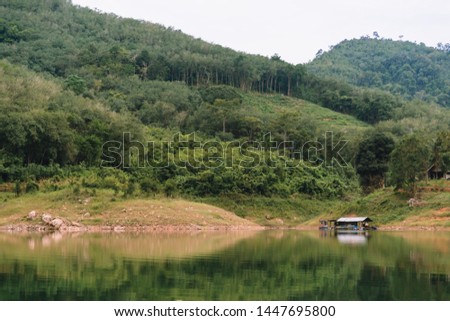 Landscape view of Bang Lang Reservoir with house raft in the lagoon and forest.